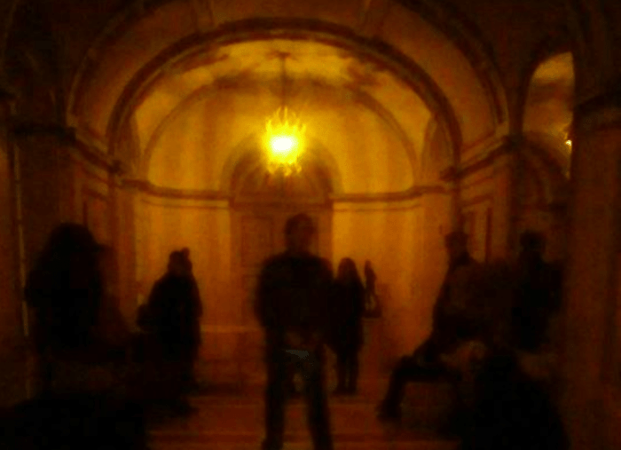 Blurry photo of guests in the dark listening to a tour guide with a flashlight.